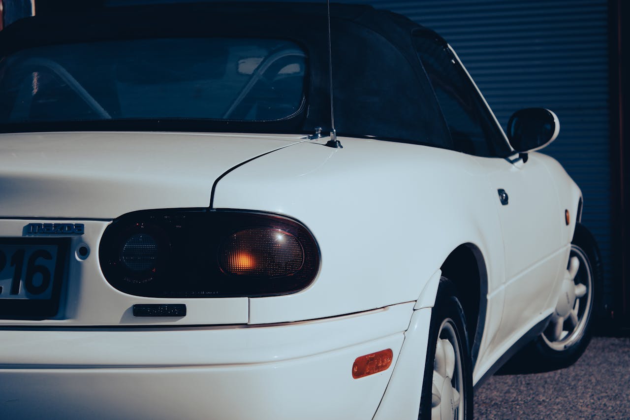 Detailed view of a classic white sports car rear in daylight, showcasing its vintage design.