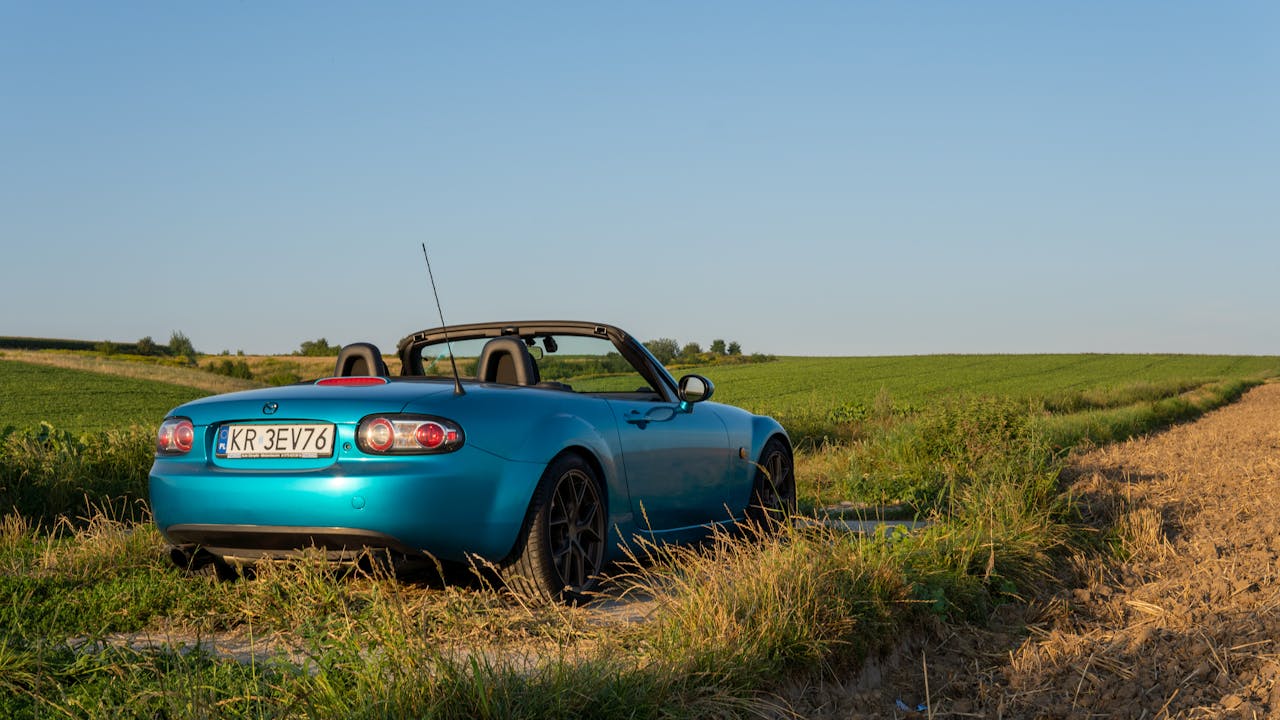 A blue convertible in the scenic countryside of Słomniki, Poland on a sunny day.