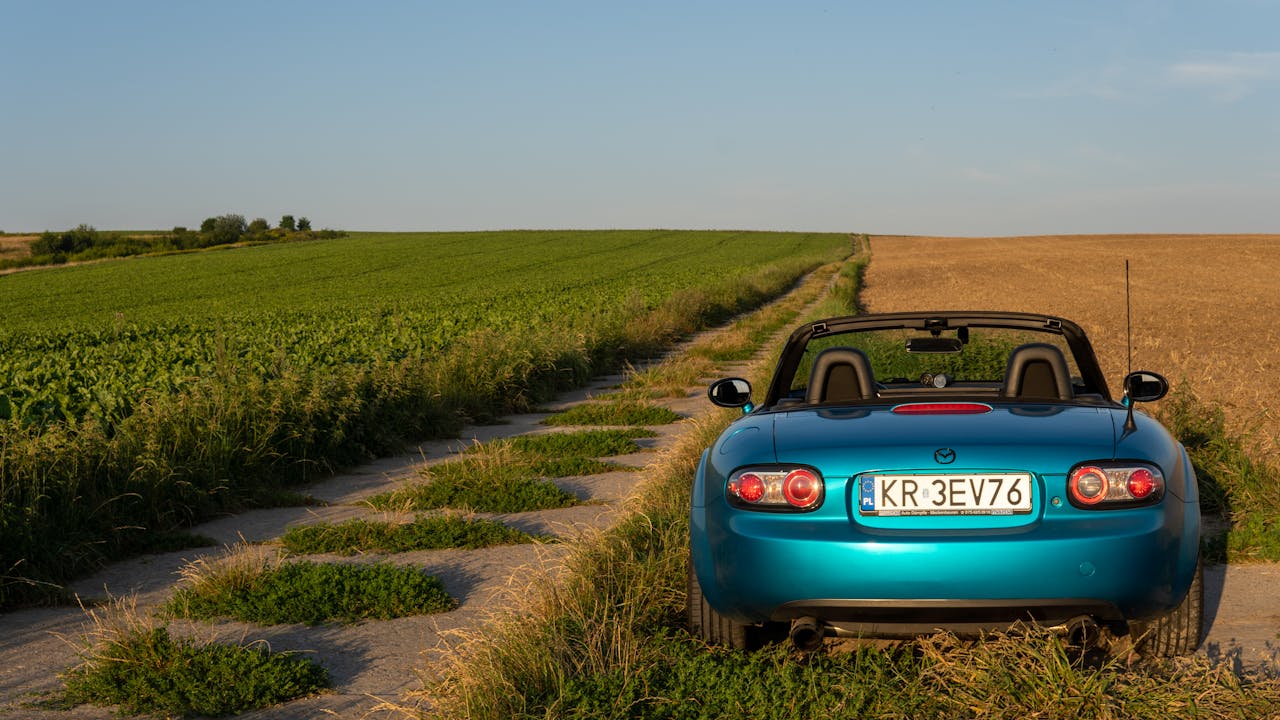 Convertible Mazda MX-5 on a picturesque rural road in Poland's countryside.